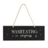 Hängeschild „Manifesting In Progress“.